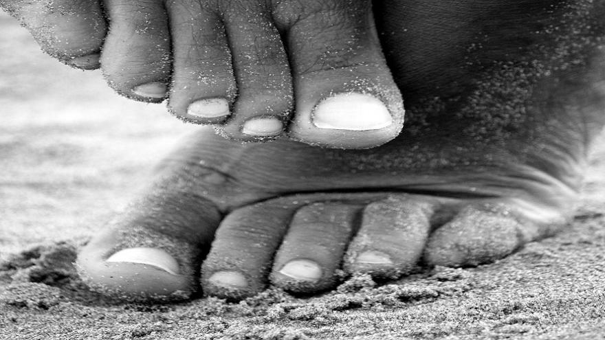 Pies en blanco y negro sobre arena de playa