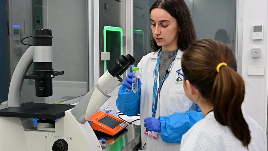 Una científica explica a una niña cómo funciona un microscopio