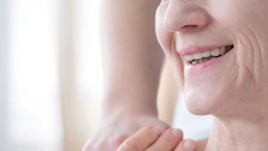 Mujer sonriendo con un pañuelo en la cabeza y coge mano médica