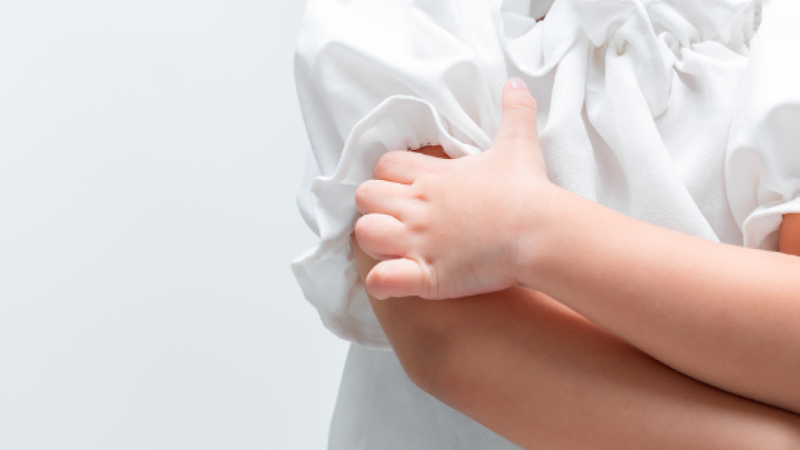 La mano izquierda de una niña pequeña rascando su brazo derecho 