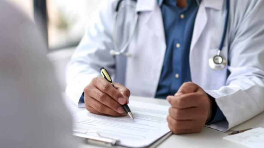 Médico escribiendo información clínica de un paciente