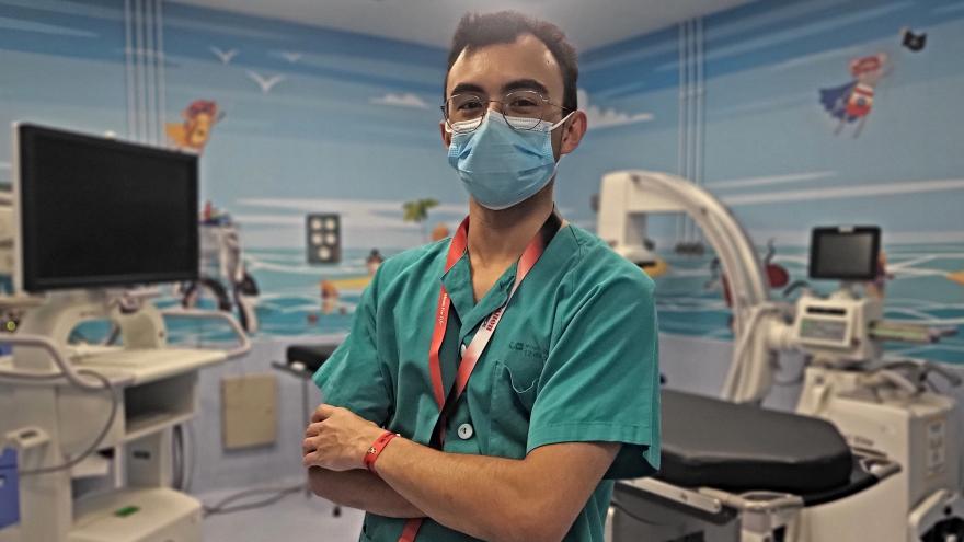 retrato de medio cuerpo de chico joven con bata blanca posando delante de laboratorio