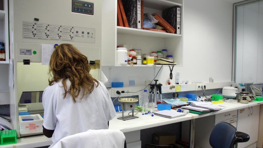 Mujer profesional de espaldas en una mesa de laboratorio.