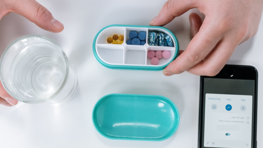 IMagen de un vaso de agua, un teléfono móvil y un pastillero