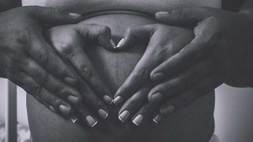 Una pareja con las manos enlazadas sobre el vientre de la mujer embarazada