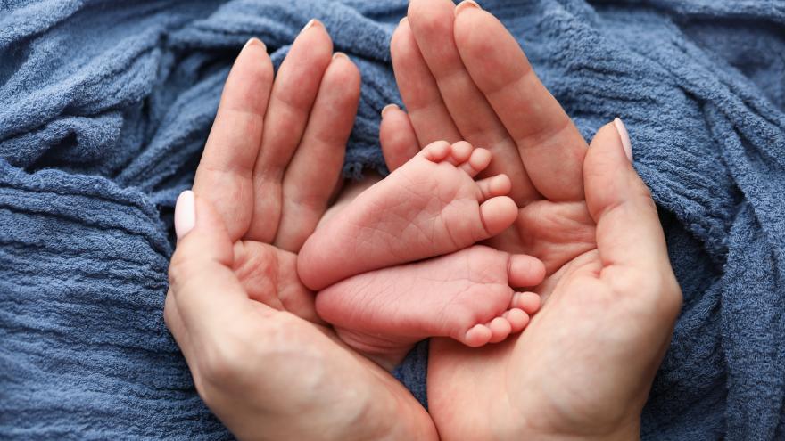 foto de los pies de un bebé entre las manos de su madre
