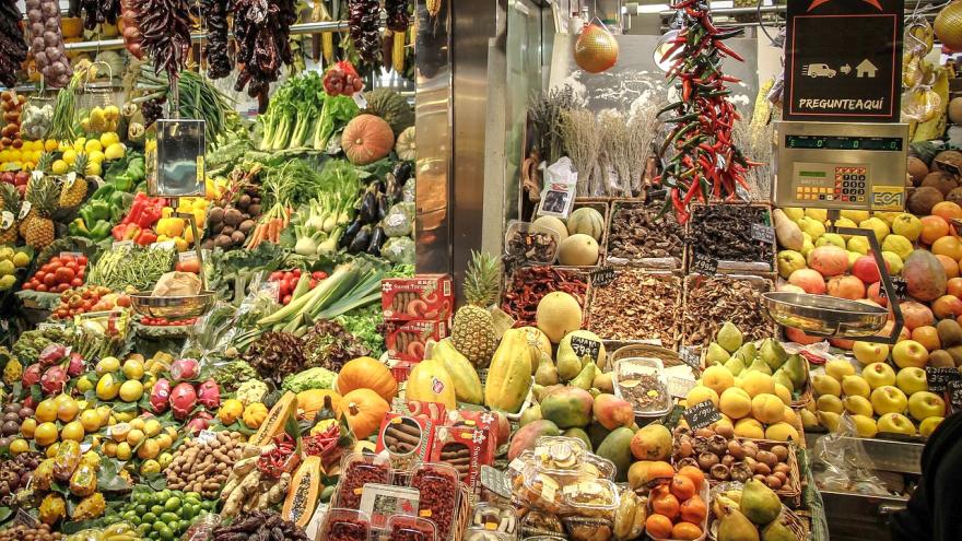 frutas y verduras a granel y envasadas en un expositor en una frutería de un mercado