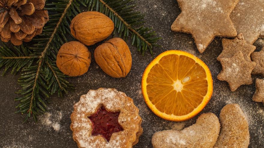 Bodegón de alimentos: nueces, naranja cortado, pastas y rama de abeto