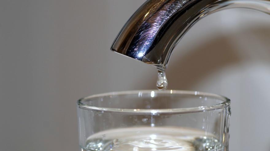 Grifo con una gota sobre un vaso con agua