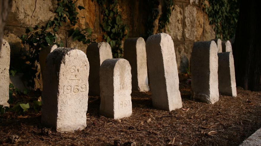 Lápidas sencillas frente a la pared de un cementerio