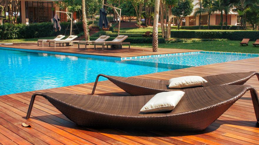 Piscina de una urbanización, con suelo de madera y tumbonas en forma de barca