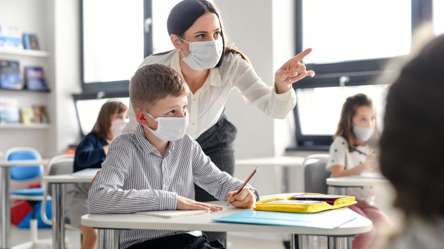 A teacher explains to a student something they see on the blackboard