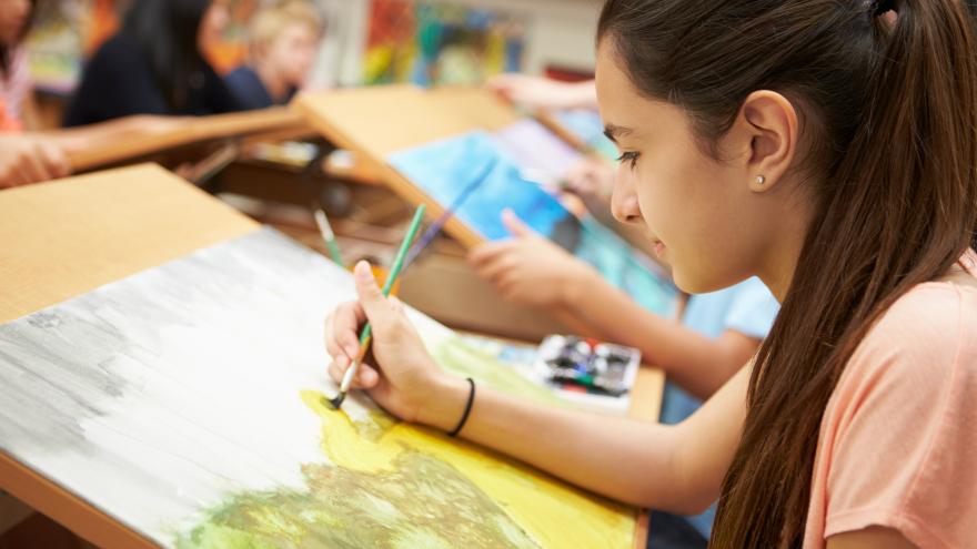 Una niña dibuja sentada en una escuela de arte