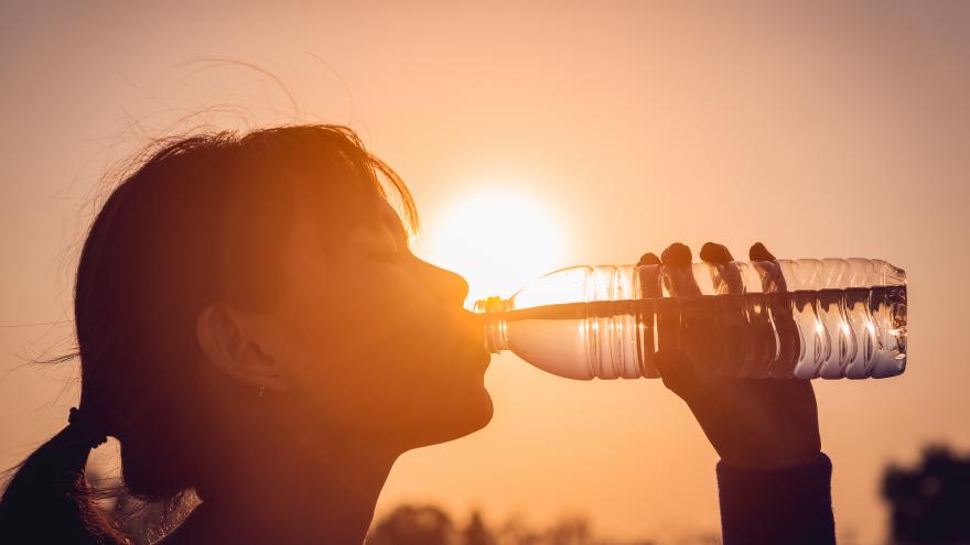 Una joven se refresca bebiendo de una botella de agua