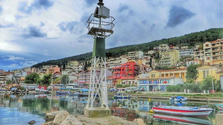 Puerto de amplhilochia en Grecia, con barcos y casas en la montaña