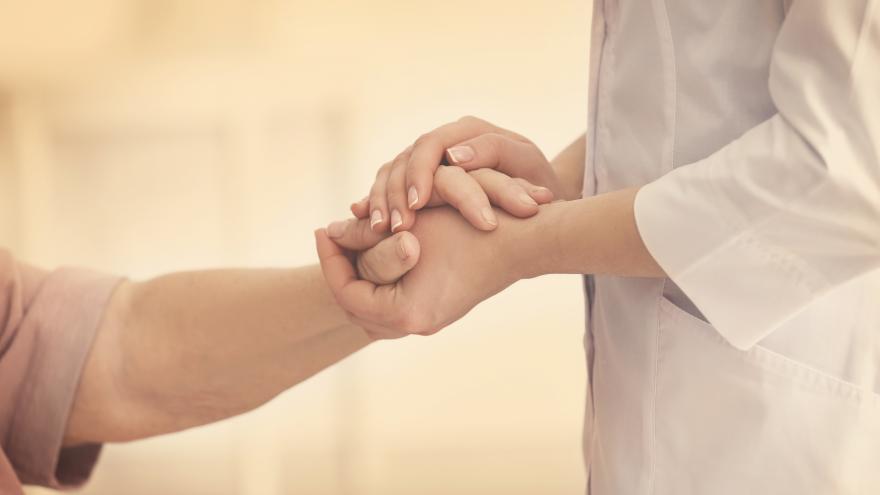 Una doctora coge las manos de una paciente