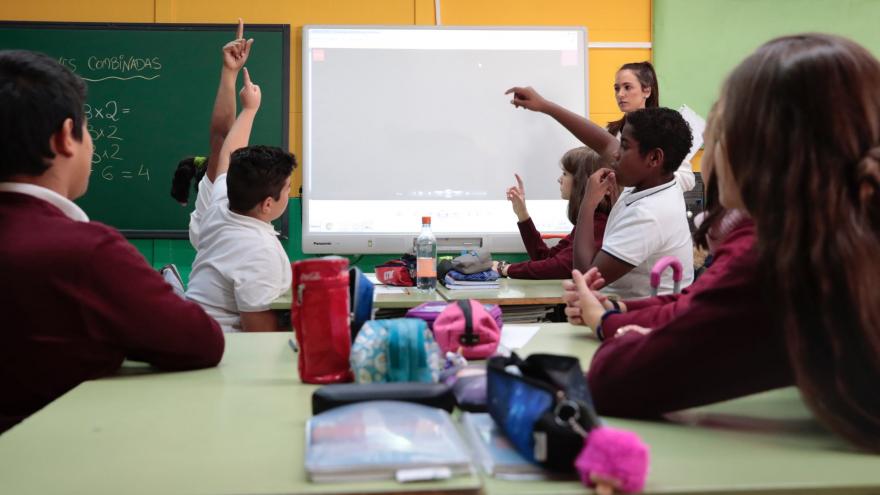 Estudiantes en clase preguntan a la profesora