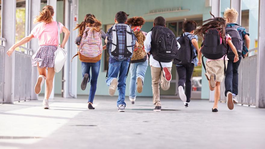 Niños con sus mochilas corriendo por un pasillo