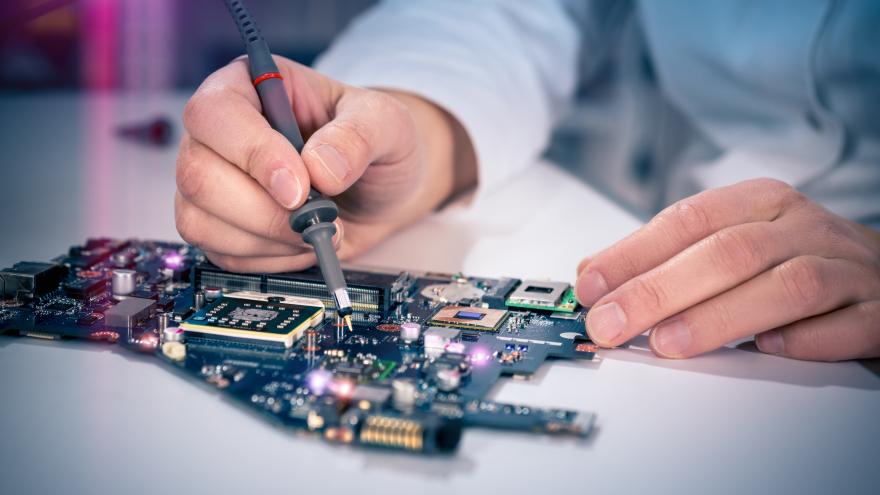 Manos manipulando con un soldador pequeño una placa electrónica