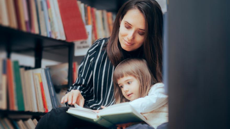 madre e hijo leen un libro en una biblioteca pública