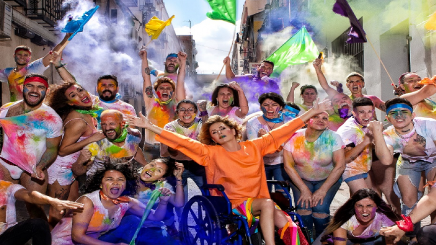 Grupo de personas con banderas y atuendo multicolor