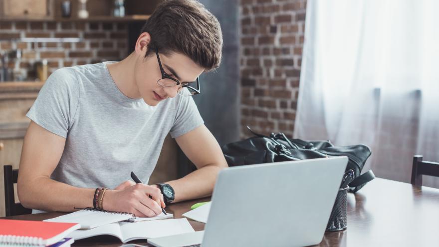Teenager sitting at a table writing