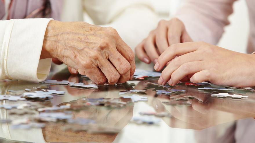 Manos de una persona mayor resolviendo un puzzle en una residencia_