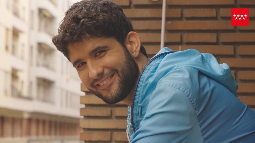 Joven con camiseta azul asomado a un balcón