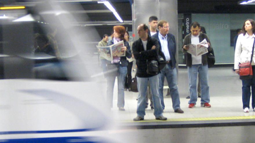 Personas esperando en andén mientras el metro entra en la estación