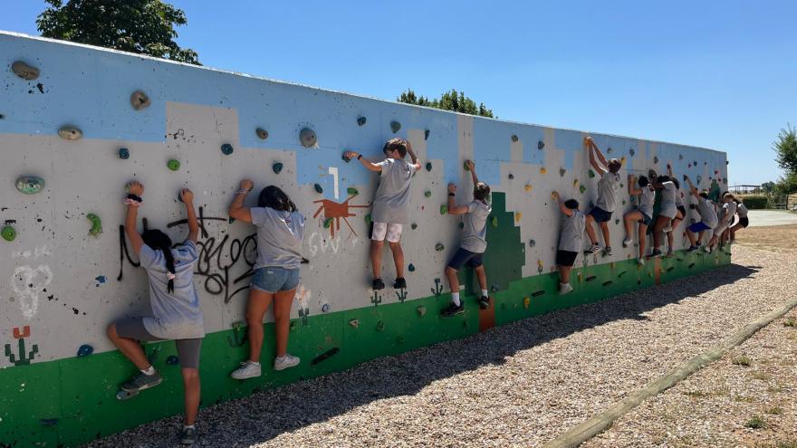 jovenes haciendo escalada por una pared