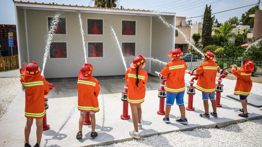 Niños manguera vestidos bomberos