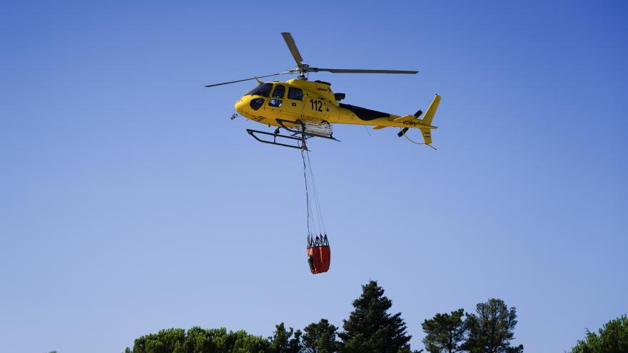 Helicóptero sobrevolando un bosque con la bolsa de agua colgando