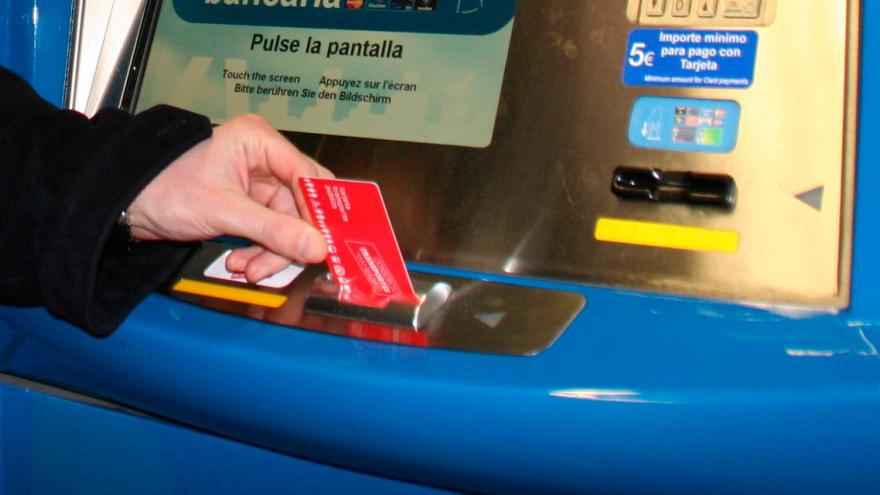 Mano introduciendo una tarjeta transporte público en una máquina  expendedora de títulos 