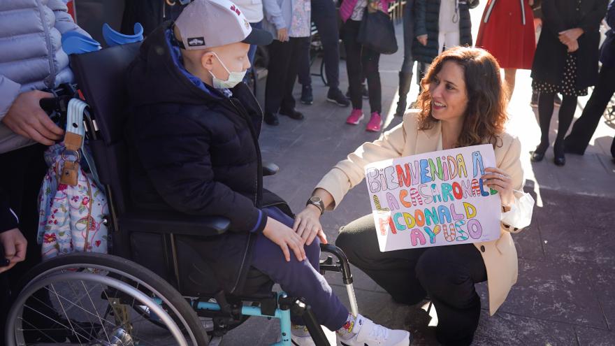La presidenta en su llegada a la visita saludando a un niño en silla de ruedas que le entrega un cartel