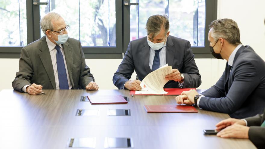 El consejero firmando el convenio sentado en una mesa junto al resto de asistentes