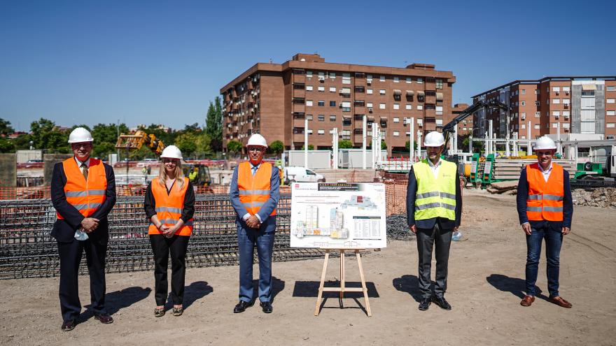 El consejero junto con el resto de miembros posan en las obras del nuevo colegio junto al plano del mismo