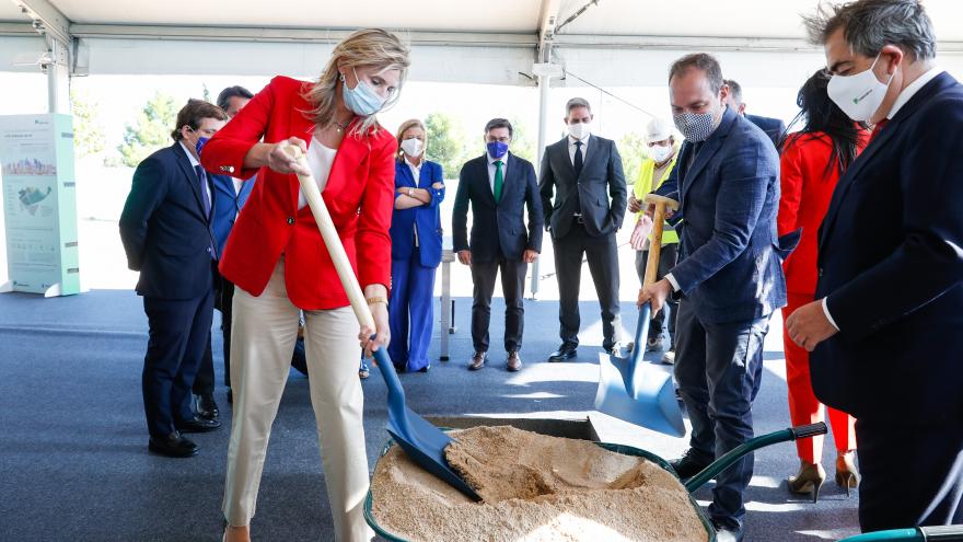 La consejera con una pala cogiendo arena de una carretilla como símbolo de la colocación de esa primera piedra