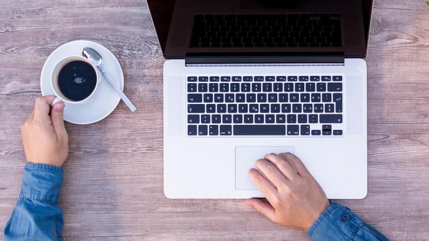 hand in coffee and another hand in computer