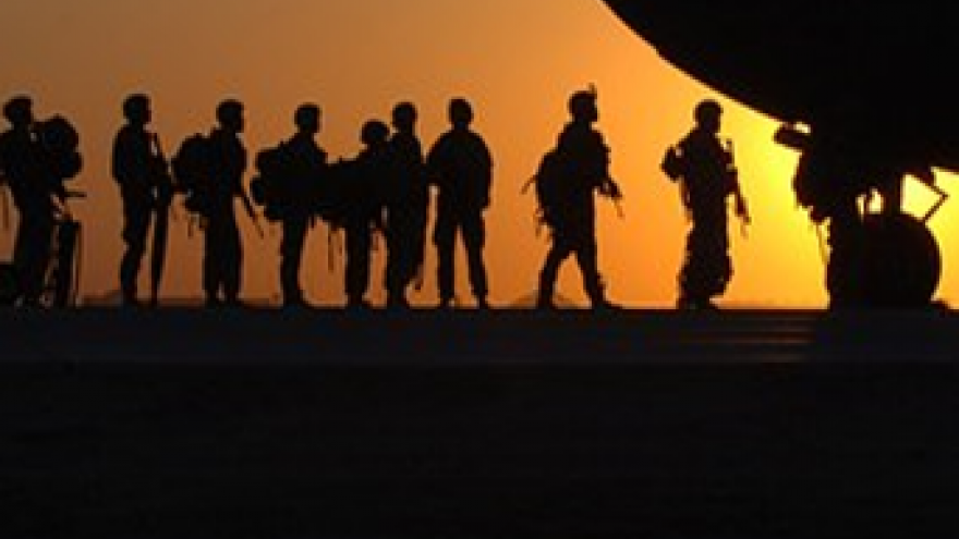 Siluetas de militares a contraluzen campaña junto a morro de avión
