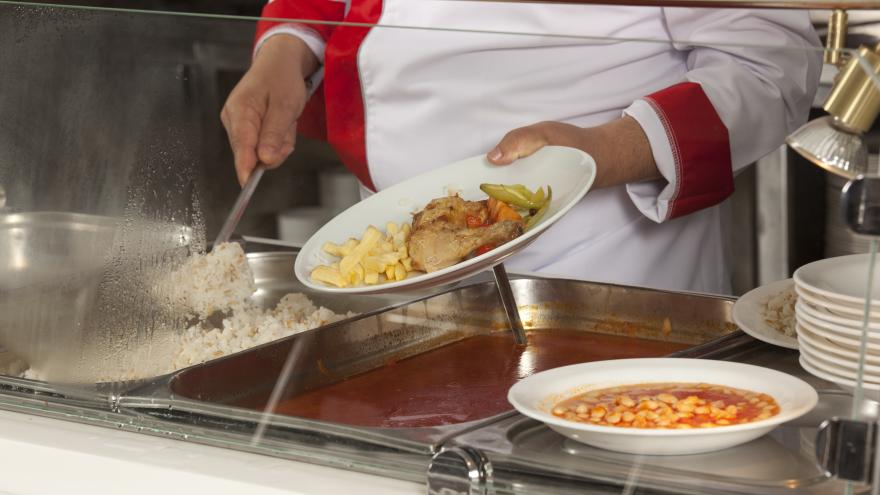 Una mujer sirve un plato de comida en un comedor