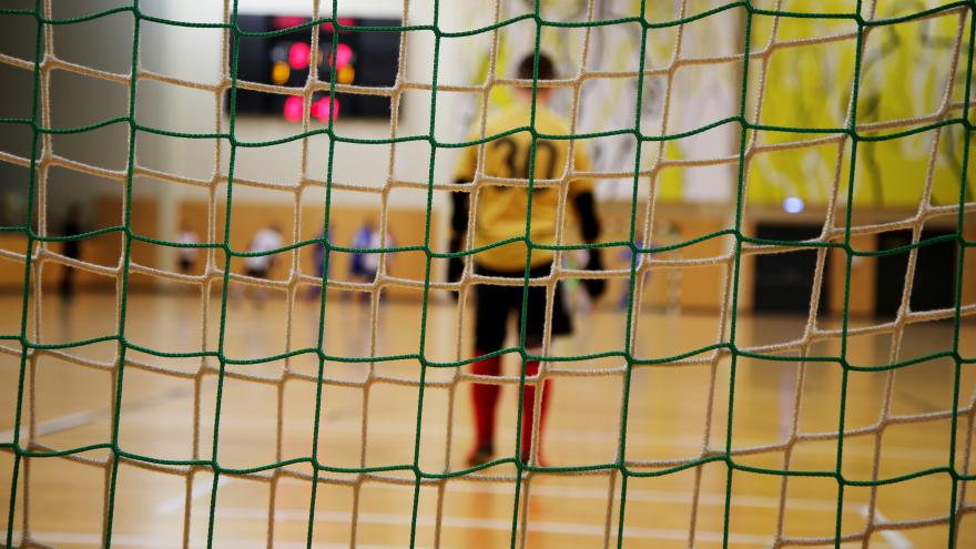 Un portero de fútbol sala de espaldas visto a través de las redes de la portería 