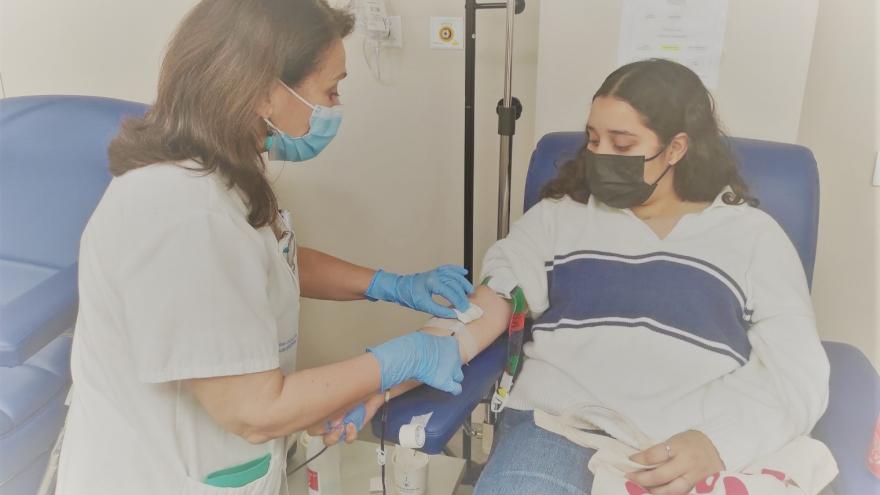 A girl donates blood in a hospital together with a nurse