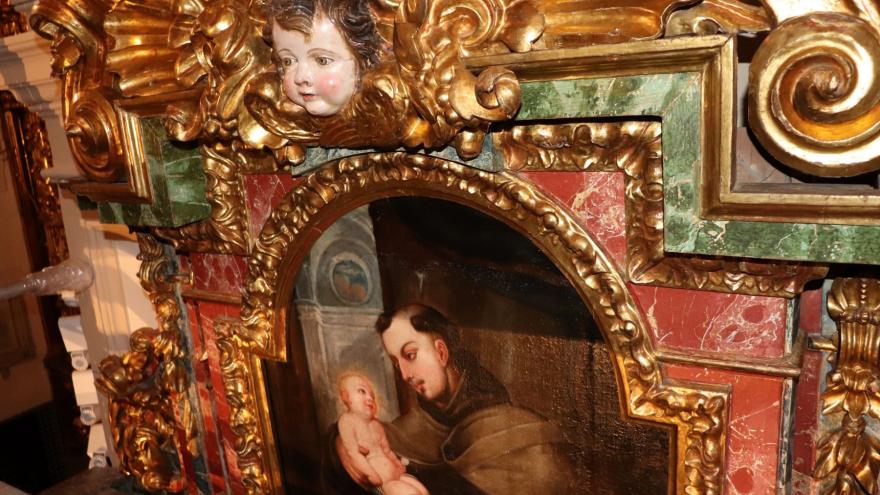 imagen de un fragmento de retablo con una cabeza de ángel esculpida y una pintura insertada en marco decorado