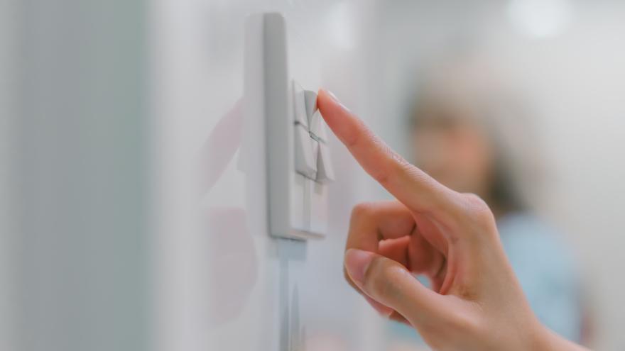 Una persona presiona un interruptor de luz