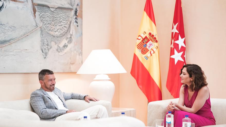 La presidenta Isabel Díaz Ayuso sentada conversando con Antonio Banderas