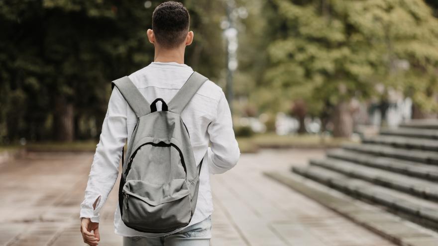 Un joven caminando de espaldas con un bolso