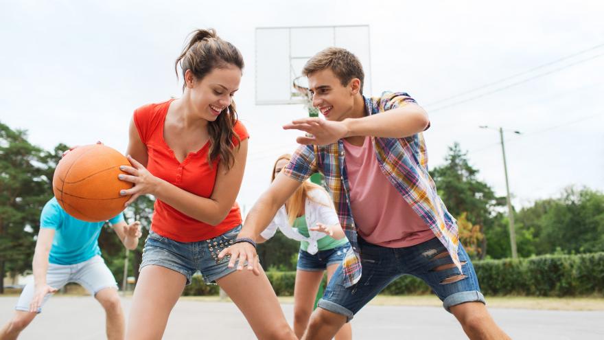 Unos jóvenes jugando al baloncesto y sonriendo