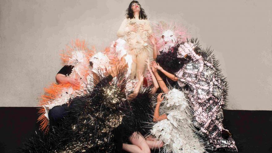 La artista Marta Pinilla en el centro con un traje llamativo rodeada de mujeres