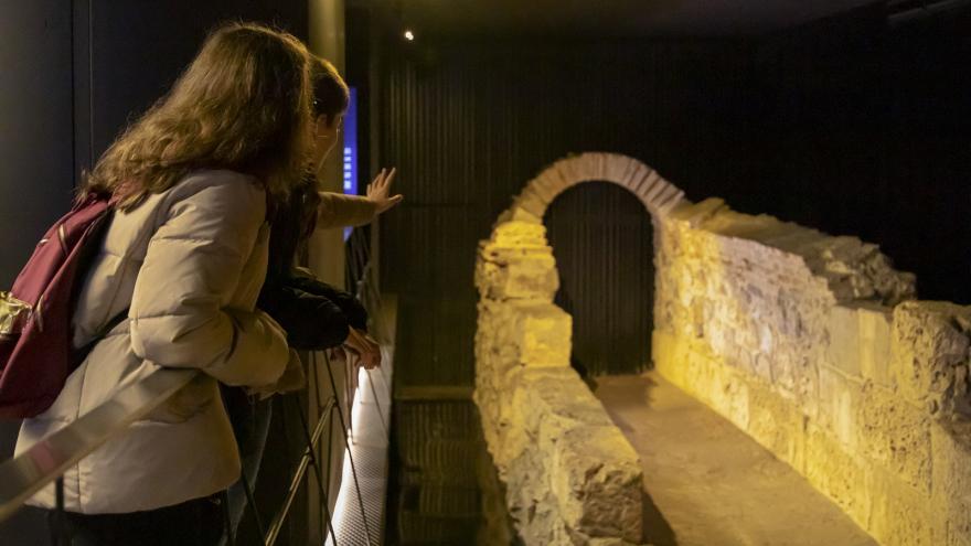 Young people point to a stone arch