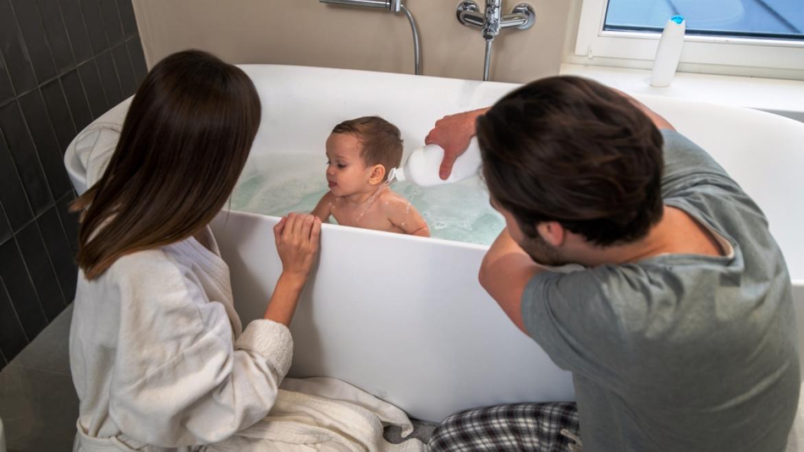 padres bañando a un bébé en una bañera